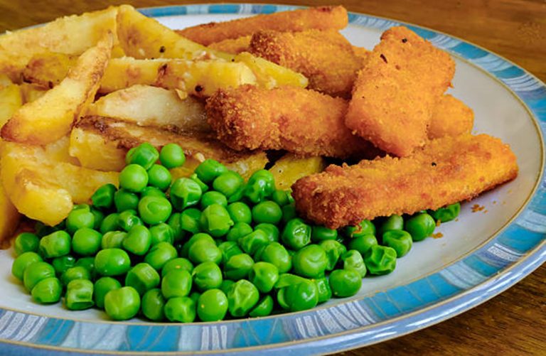 A plate with Crispy Baked Fish Fingers, homemade potato wedges, and a serving of green peas—perfect for a healthy family dinner.