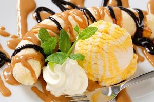 A tall glass of creamy banana caramel swirl milkshake topped with whipped cream, caramel drizzle, and banana slices.”