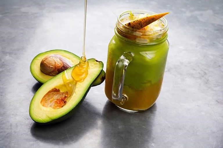 A glass of creamy Avocado & Honey Shake topped with a drizzle of honey and a sprinkle of chia seeds.