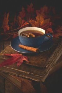 A steaming cup of Cinnamon Leaf Tea surrounded by cinnamon sticks and dried cinnamon leaves on a rustic table.