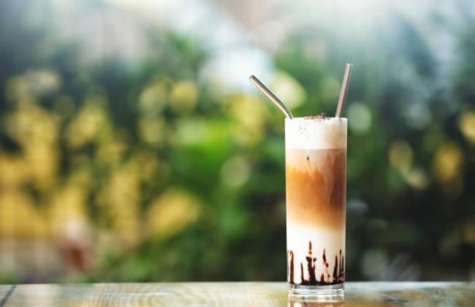 A tall glass of Espresso Mocha Shake topped with whipped cream, cocoa dust, and coffee beans on a rustic wooden table.