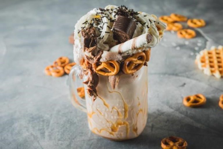 A glass of Salted Caramel Pretzel Shake topped with whipped cream, caramel drizzle, and crushed pretzels.